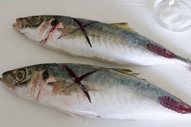 塩をまぶしたあじを2尾置いたまな板