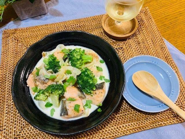 パセリを散らした、鮭とブロッコリーのクリーム煮が入った黒い皿