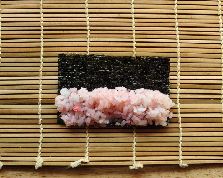 巻きす、海苔の上に桜でんぶ入りの寿司飯が置かれている