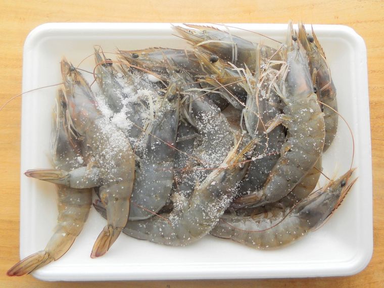 白いトレーに入れたえびに塩をまぶしている様子