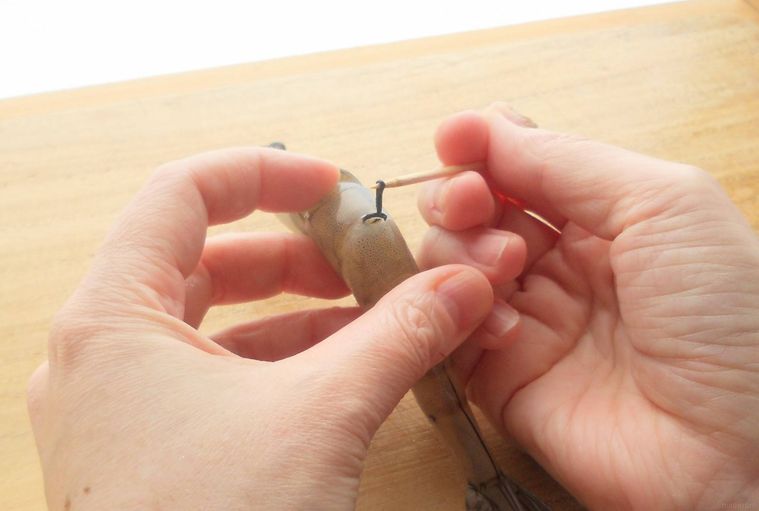 爪楊枝をえびの節に刺して、背わたを取っている様子