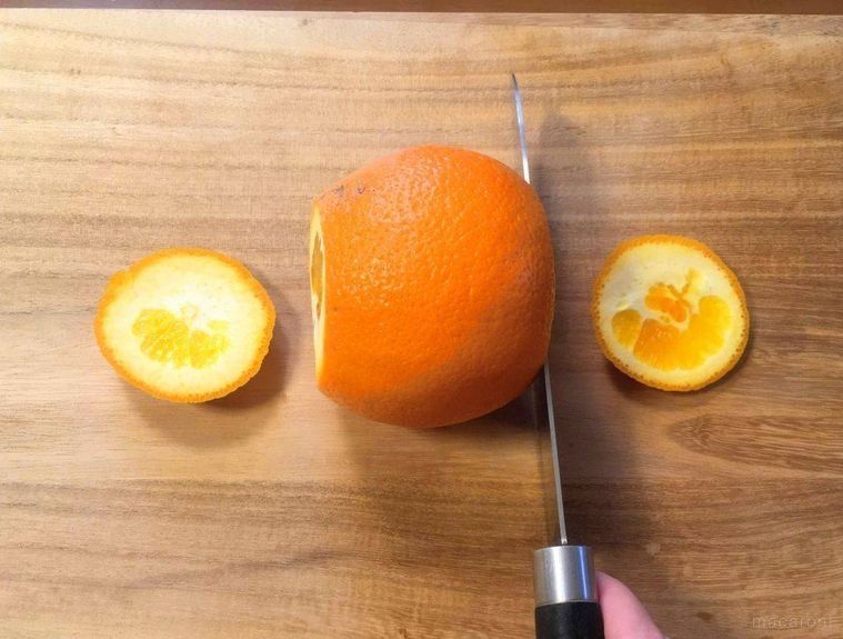 オレンジのヘタと底の部分を切り落としている様子