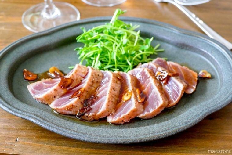 皿の上に盛り付けられたマグロステーキ、まわりにはグラスが置かれている