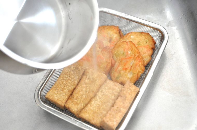 厚揚げとさつま揚げに熱湯をかけて油切りしている様子