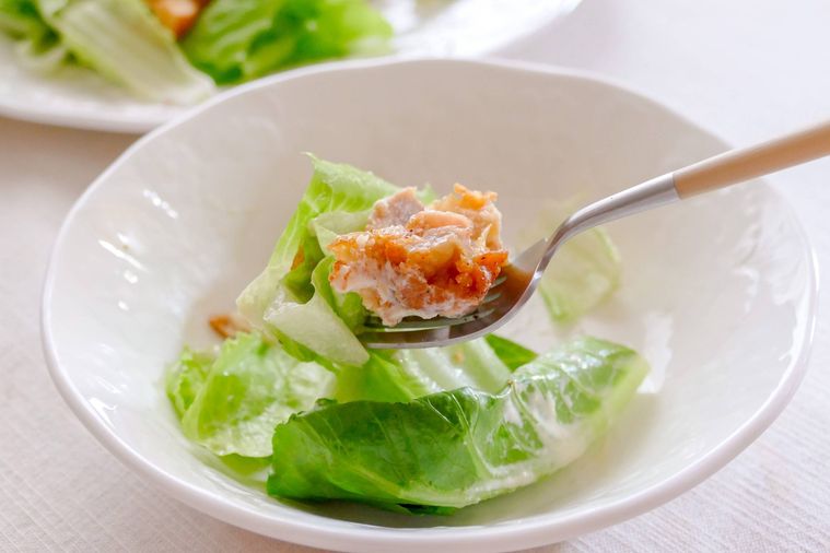 オリジナルチキン入りのシーザーサラダをフォークで持ち上げる様子