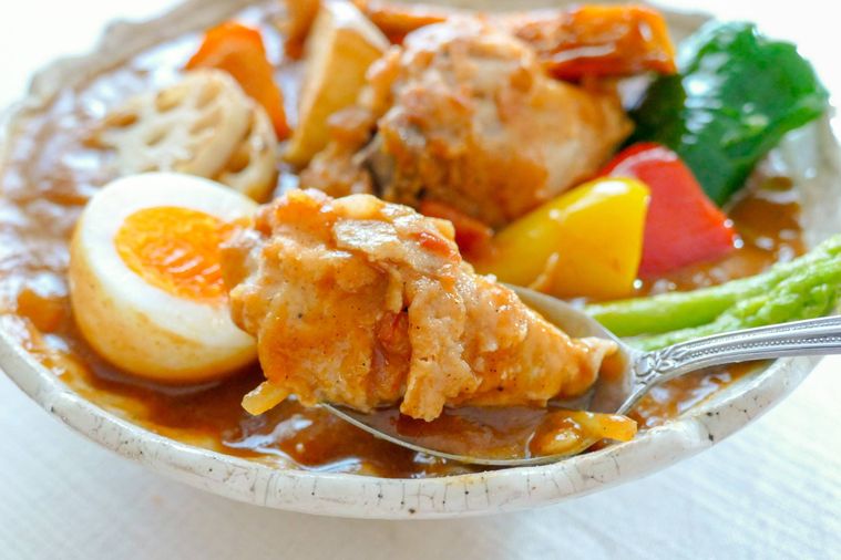 スープカレーに入っているオリジナルチキンをスプーンですくう様子