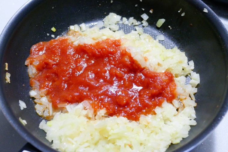 炒めたみじん切り玉ねぎとにんにくみじんにカットトマト缶を加えた様子
