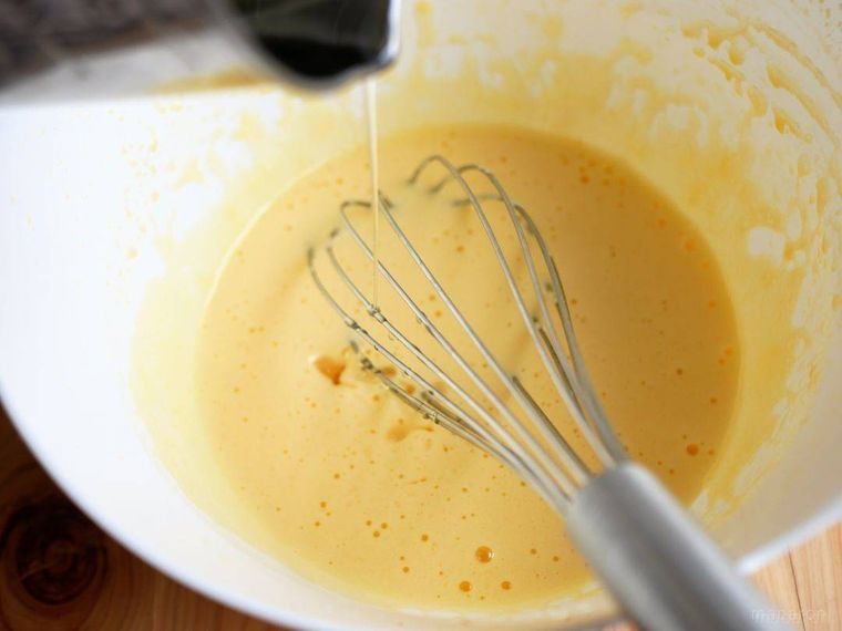 白いボウルに入った卵黄や酢などを混ぜたものに、サラダ油を少しずつ加えている様子