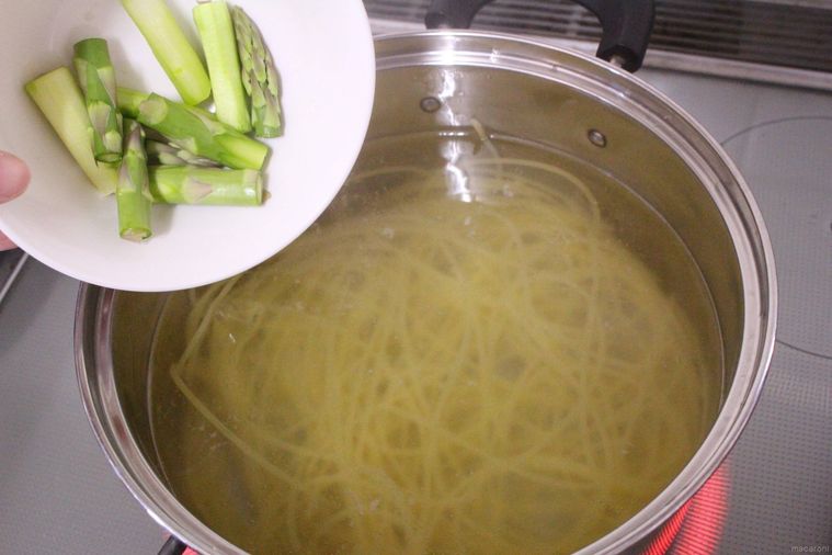 スパゲッティをゆでている鍋にアスパラを入れる様子