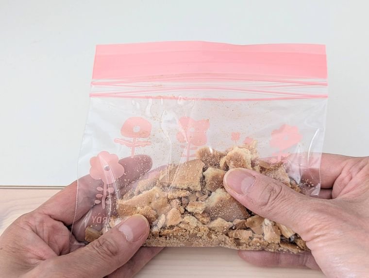 保存袋に入ったビスケットを手で砕いている様子