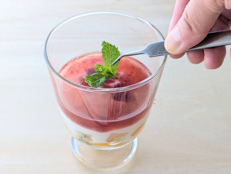 フルーチェとヨーグルトの3層デザートにミントをトッピングして仕上げる様子