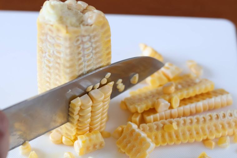 とうもろこしの身を包丁で削いでいる