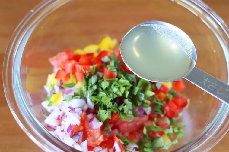 野菜の入ったボウルに調味料を加えている