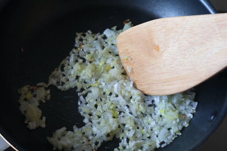 フライパンで長ねぎと生姜を炒めている