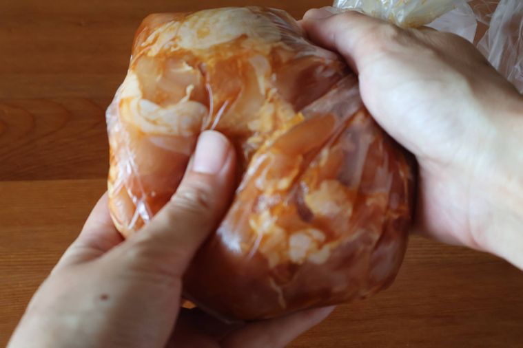 ポリ袋に入れた鶏肉をもみ込んでいる