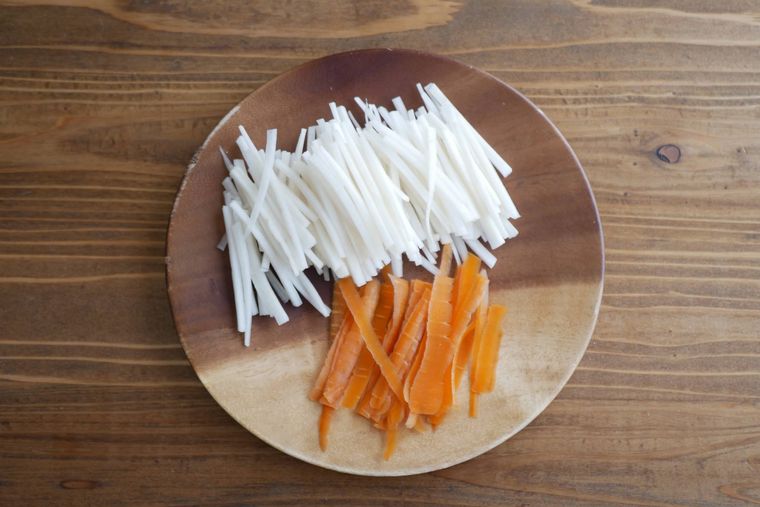 木製の丸皿に千切りの大根の皮とにんじんの皮がのっている。