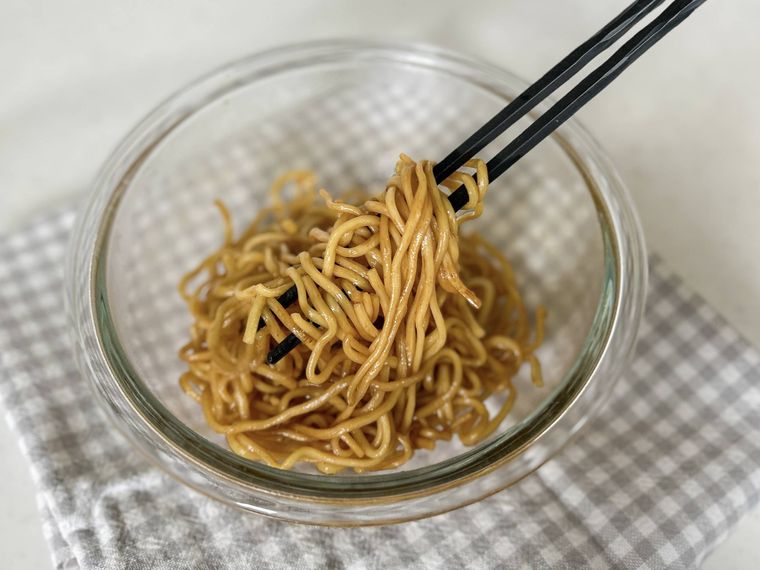 耐熱ボウルに入った焼きそば、焼きそばの粉末ソース、オイスターソース、酒、ごま油を混ぜる