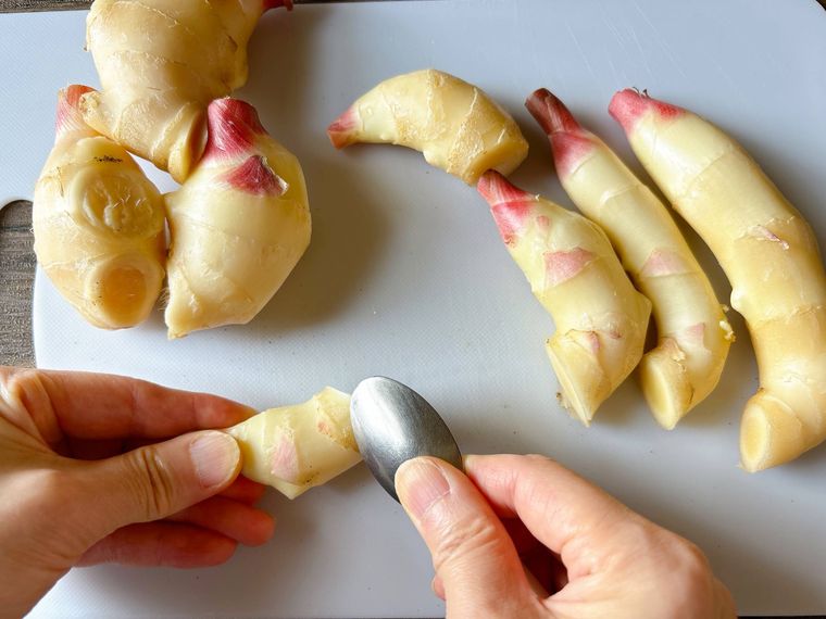 スプーンで新生姜の皮を削る様子