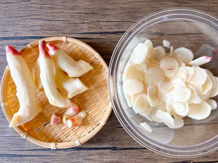 ザルにおかれた新生姜の新芽、ボウルに入ったスライスした新生姜