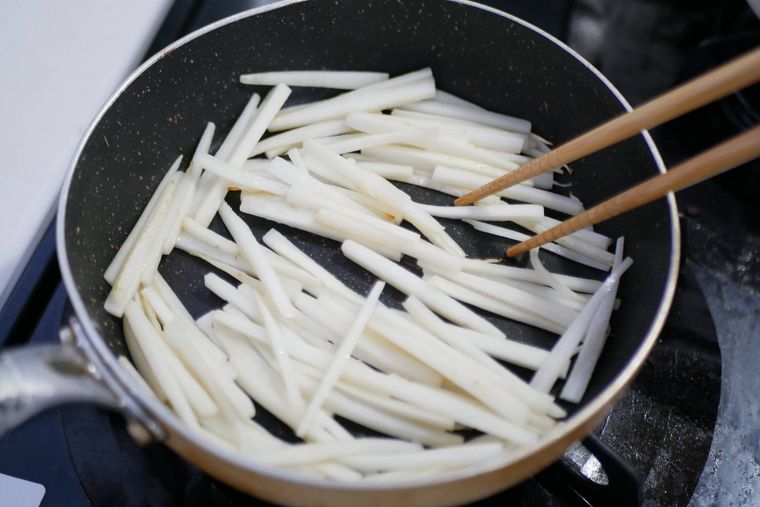 フライパンで大根の皮をごま油で炒めている様子