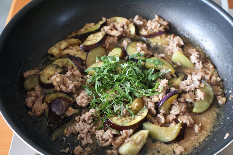 炒めたなすとひき肉の上にせん切りの大葉がのっている