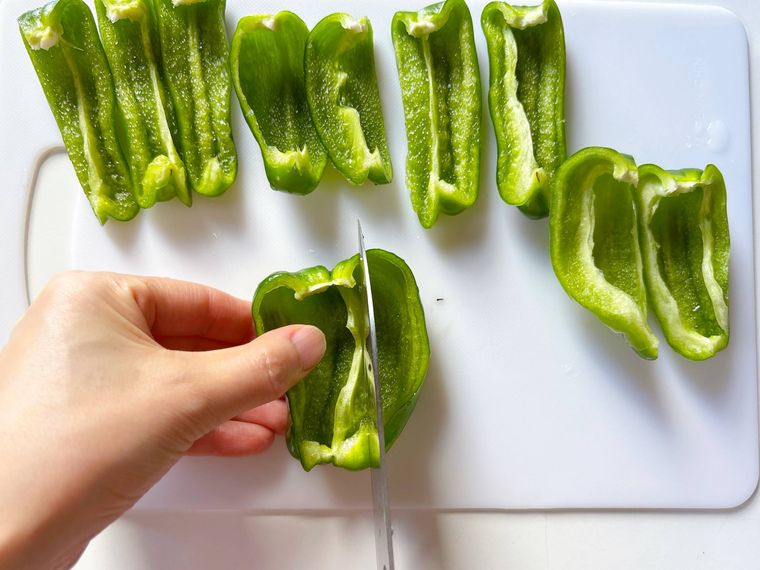 半分にカットしたピーマンを切る様子