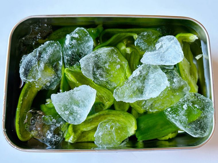 蓋付きの保存容器に氷水とピーマンを入れたもの