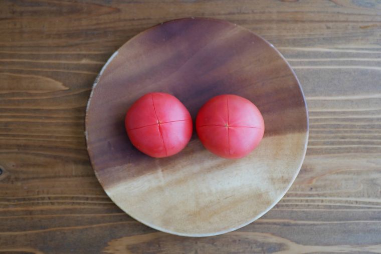 おしりに十字の切れ込みを入れたトマト2個