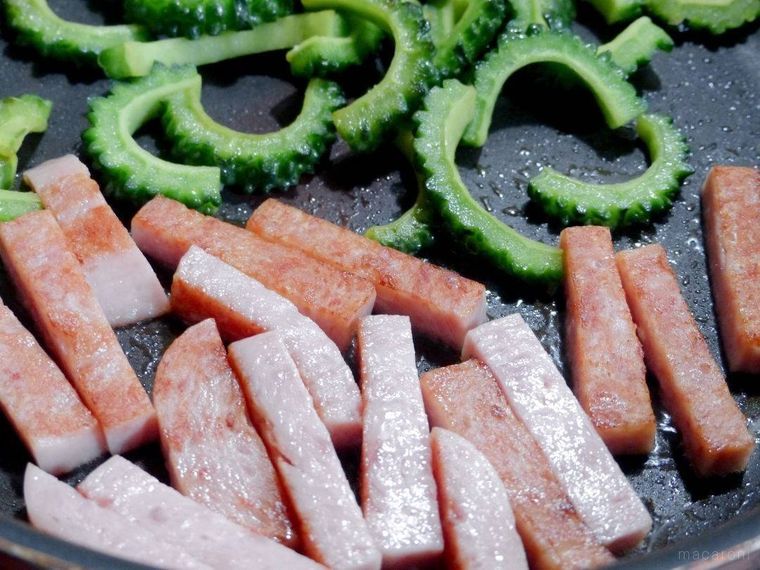 フライパンの手前でスパムを炒め、奥でゴーヤを炒める様子