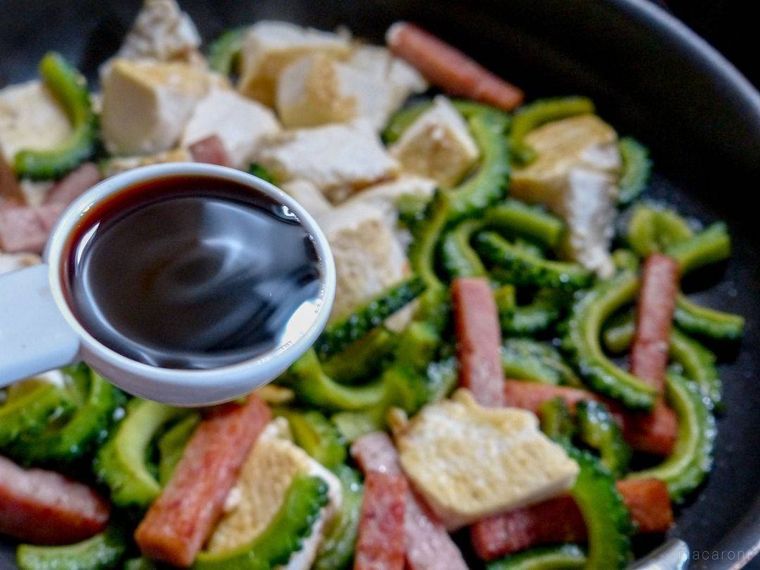 具材を炒めているフライパンと、めんつゆを入れたスプーン