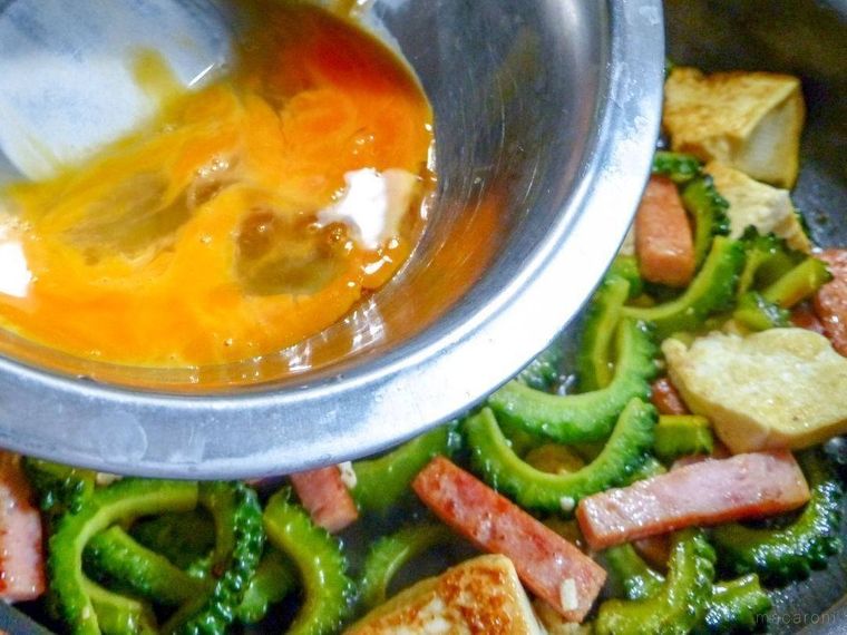 具材を炒めたフライパンに、溶き卵を加えようとしている様子