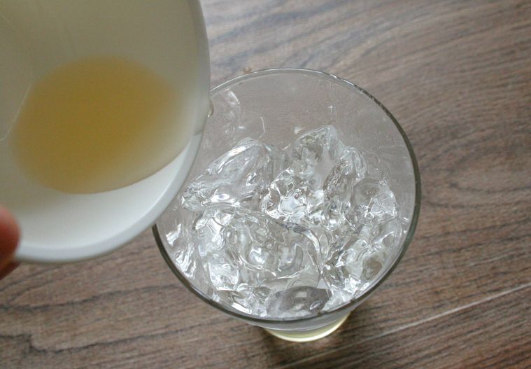 氷の入ったタンブラーグラスにウイスキーを入れている様子
