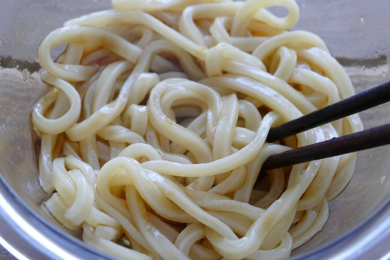 うどんに調味料を絡める様子