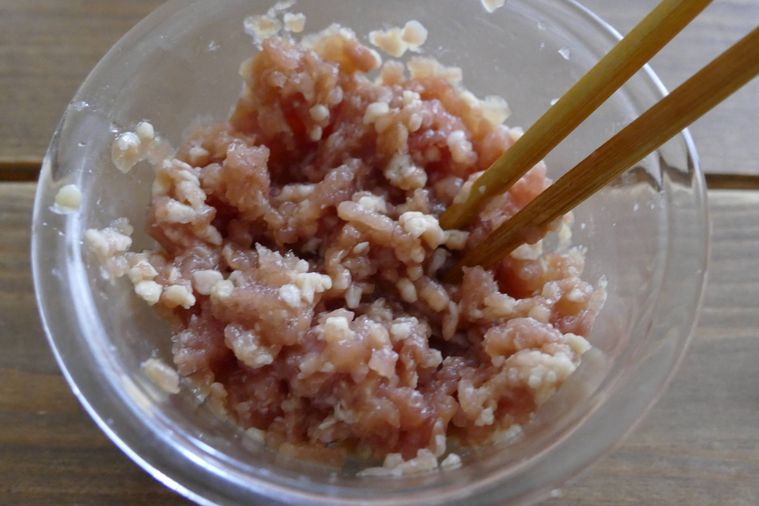 鶏ひき肉に調味料を加えて箸で混ぜる様子