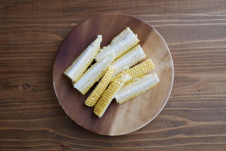 8等分に切られたとうもろこしが木製の皿の上に盛られている