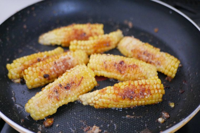 とうもろこしの唐揚げにバターしょうゆを絡める様子