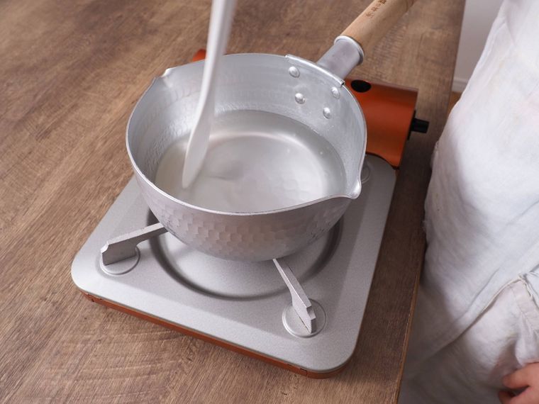 鍋を火にかけて、ゴムベラで混ぜている