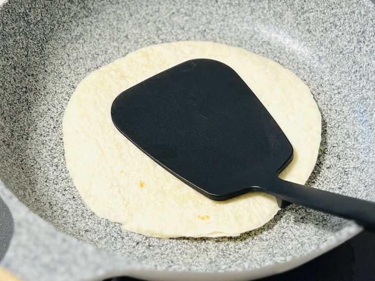 フライ返しで押さえながらトルティーヤを焼いている様子