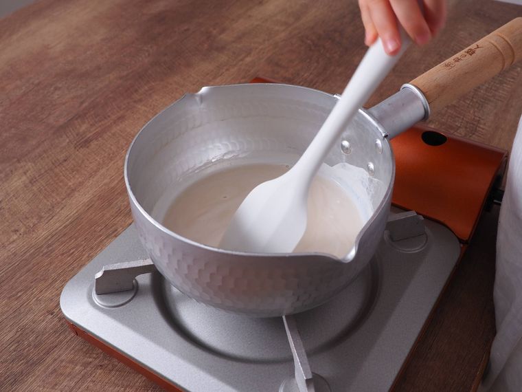 鍋の中の豆乳をゴムベラで混ぜている。