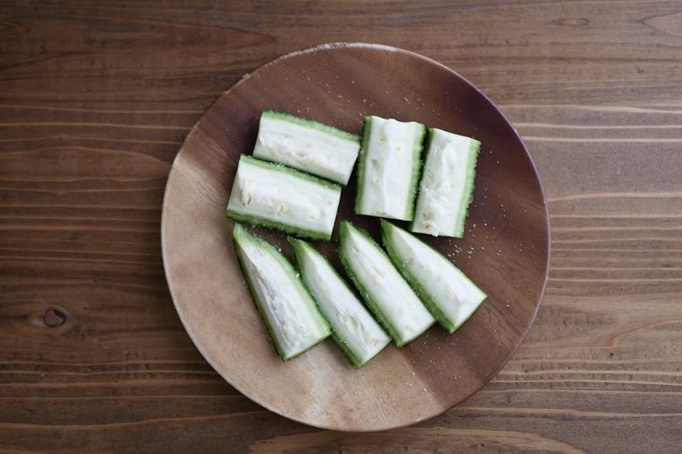 肉巻きように切ったゴーヤに塩こしょうをふる様子