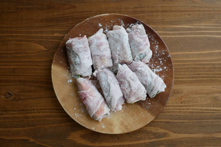 ゴーヤに豚バラ肉を巻き、片栗粉をまぶす様子