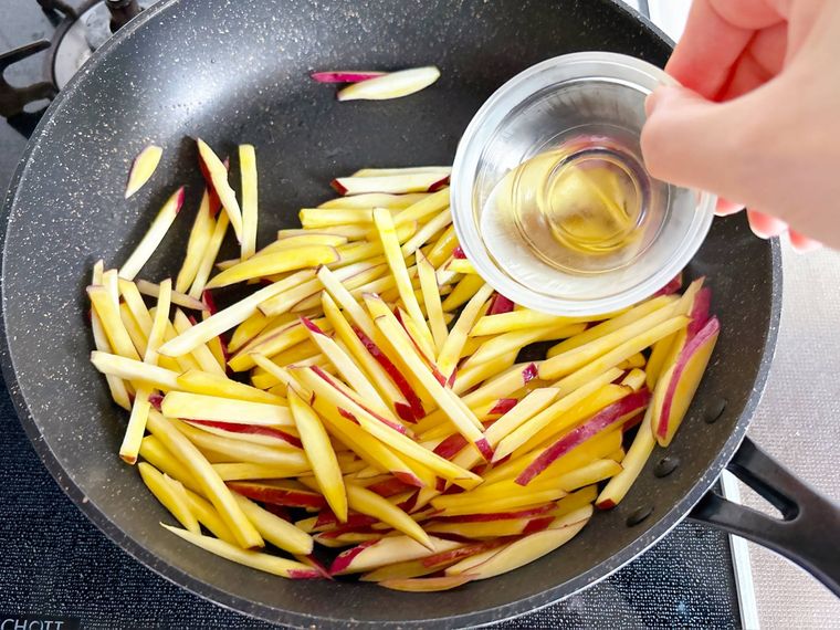 さつまいもを炒めているところにみりんを入れる様子