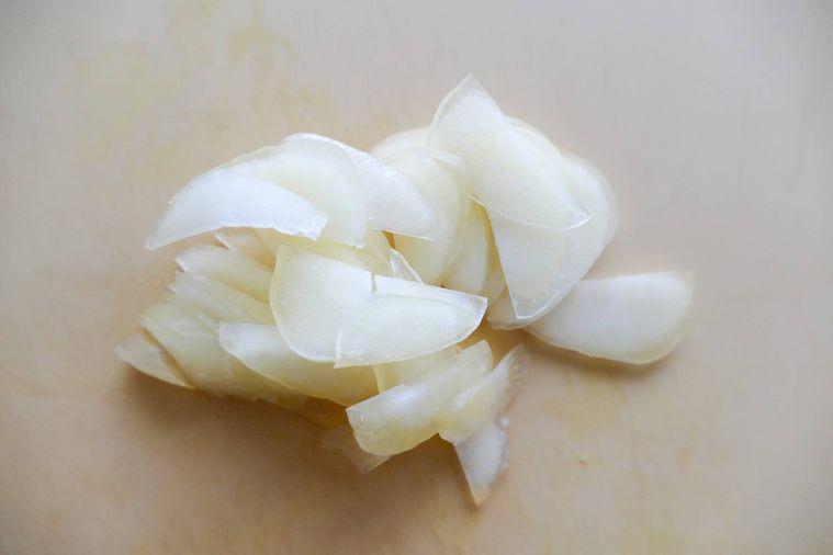 薄切りにんにくがのっているまな板