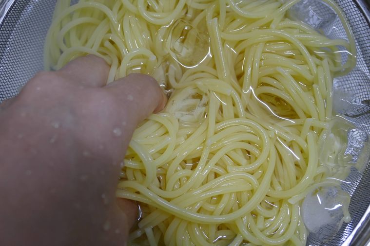 スパゲッティを手で混ぜながら氷水で冷やす様子