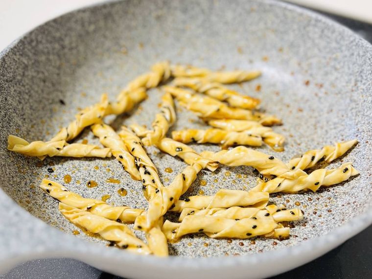 味付けをした餃子の皮に黒いりごまを散らした様子