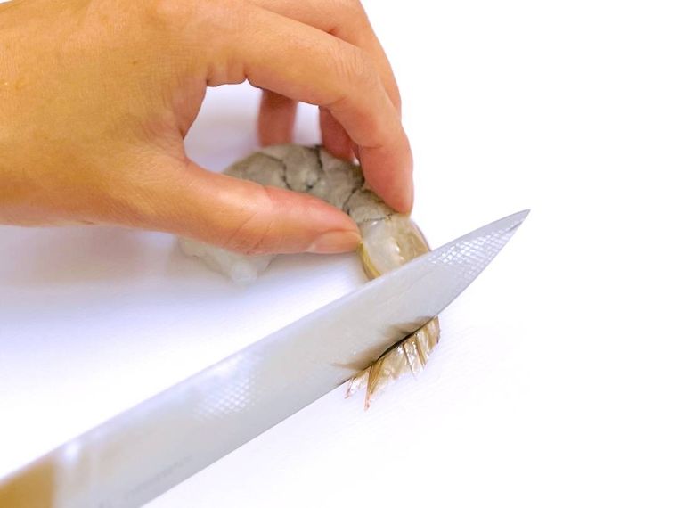 包丁の背でえびの尾をしごいている様子