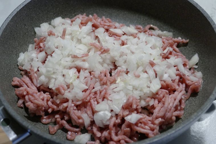 合い挽き肉とみじん切り玉ねぎが入っているフライパン