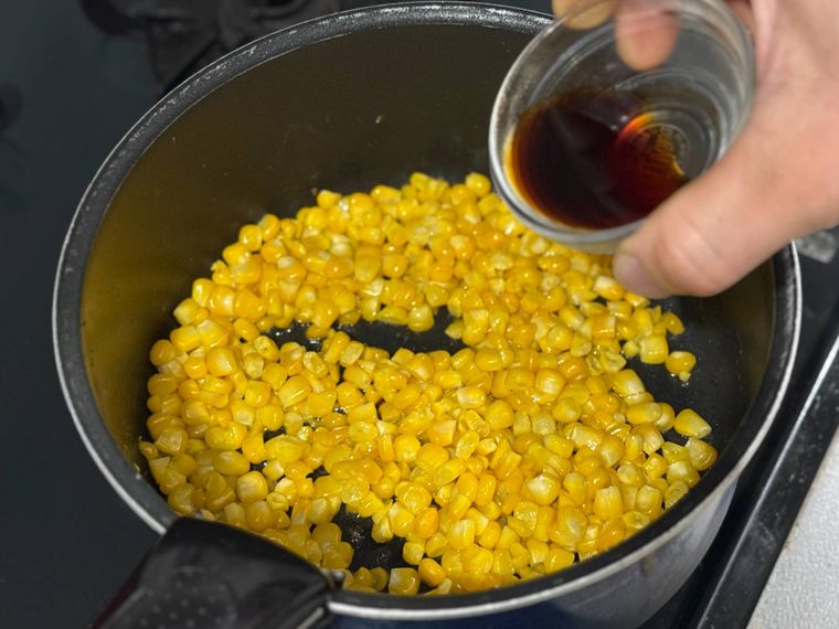 とうもろこしの入った鍋にしょうゆを加えるところ