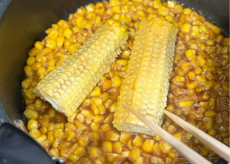 鍋に入ったとうもろこしの実と芯を煮る