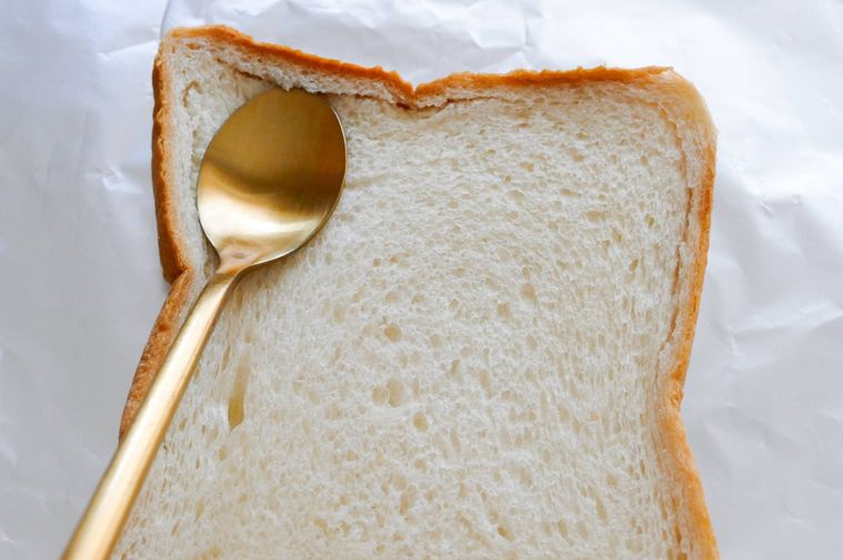 スプーンの背で食パンのふちを押す様子